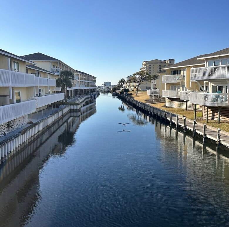 Glass-calm protected canal at Sandpiper Cove with a heron flying low over the water