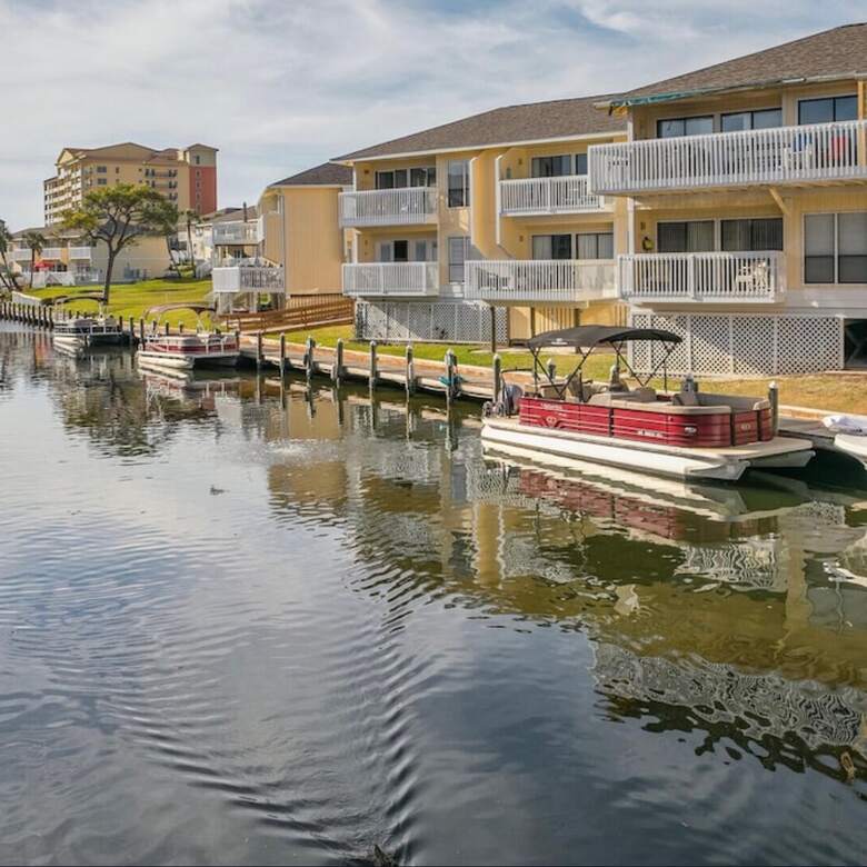 Pontoon boats tied up along the canal seawall beside the condos
